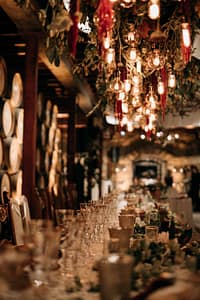 Wedding reception indoors at V. Sattui with custom hanging floral display and 40 Edison pendants over head table.