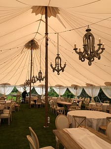 Wedding in a Zephyr tent at Meadowood in Napa Valley. Rustic wood chandeliers and market string lighting over guest tables.