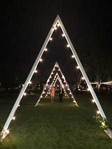 Outdoor wedding reception at The Maples with custom made triangle arches with market string lighting following interior outline of each arch.